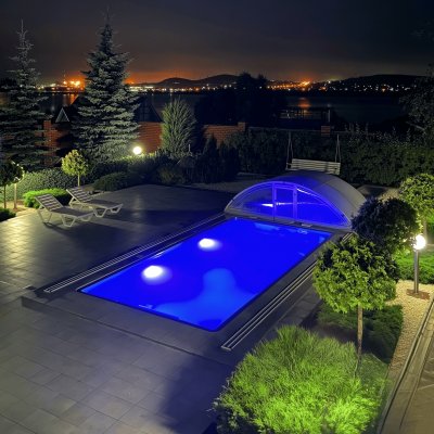 Прямоугольный бассейн с синей подсветкой и раздвижным куполом ночью